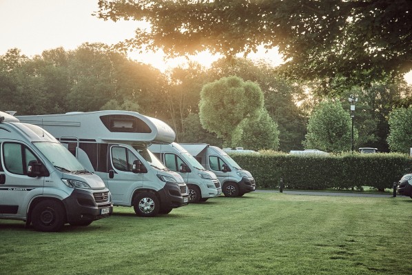 Nebeneinander geparkte Wohnmobile auf grasbewachsenen Wohnmobilstellplätzen