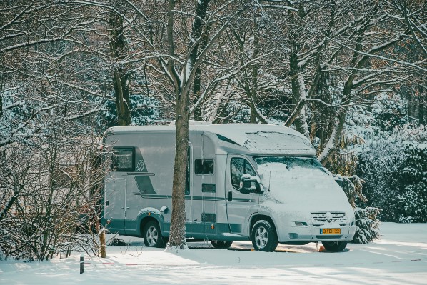 Camper in de sneeuw onder bomen