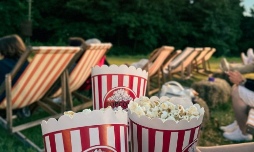 Mensen kijken film in buitenlucht op houten ligstoelen met popcorn