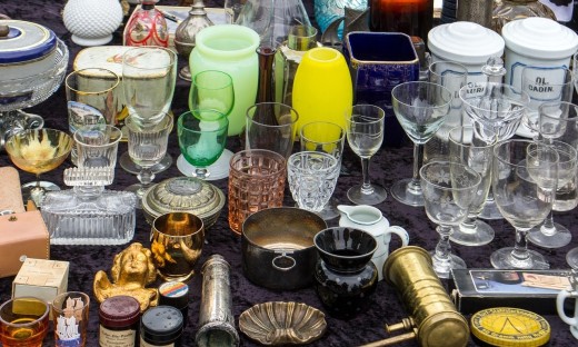 Glazen en antieke spullen staan uitgestald op een kraampje op een vlooienmarkt