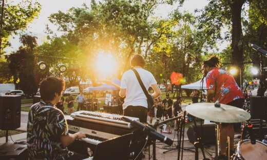 Optreden in de buitenlucht, man zit achter de piano, man met gitaar en man met microfoon